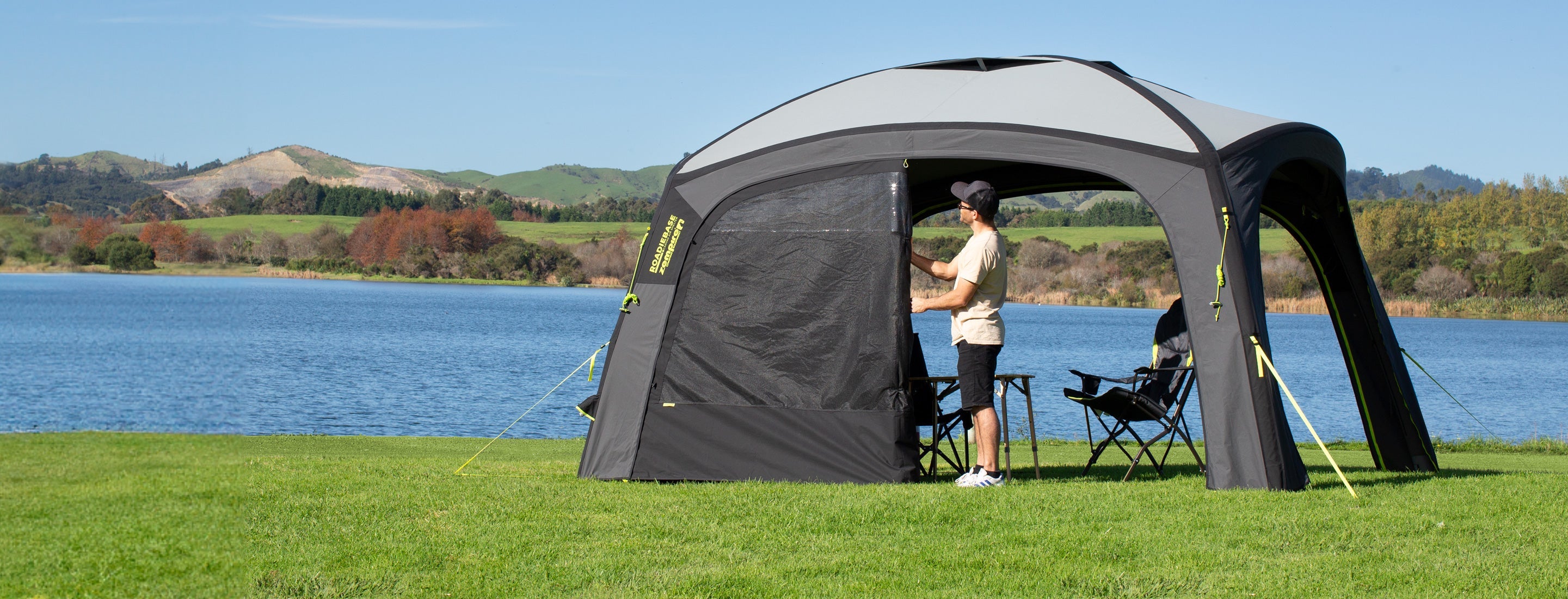 Inflatable camping tent set up by a lake with people inside